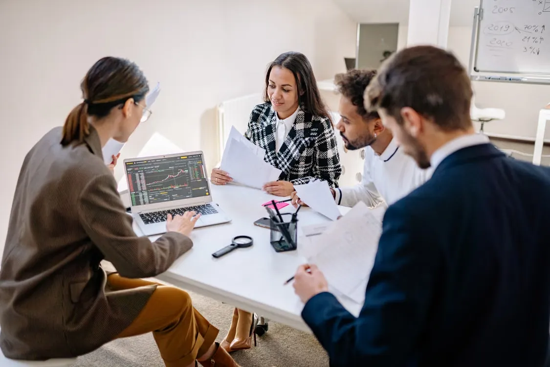 Business professionals collaborating around a laptop — illustrative stock photo